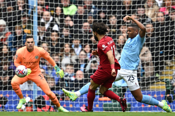 Liverpool's Egyptian striker Mohamed Salah (C) shoots past Manchester City's Swiss defender Manuel Akanji (R) and Manchester City's Brazilian goalkeeper Ederson (L) to score the opening goal of the English Premier League football match between Manchester City and Liverpool at the Etihad Stadium in Manchester, north west England, on April 1, 2023. (Photo by Paul ELLIS / AFP) / RESTRICTED TO EDITORIAL USE. No use with unauthorized audio, video, data, fixture lists, club/league logos or 'live' services. Online in-match use limited to 120 images. An additional 40 images may be used in extra time. No video emulation. Social media in-match use limited to 120 images. An additional 40 images may be used in extra time. No use in betting publications, games or single club/league/player publications. / (Photo by PAUL ELLIS/AFP via Getty Images)