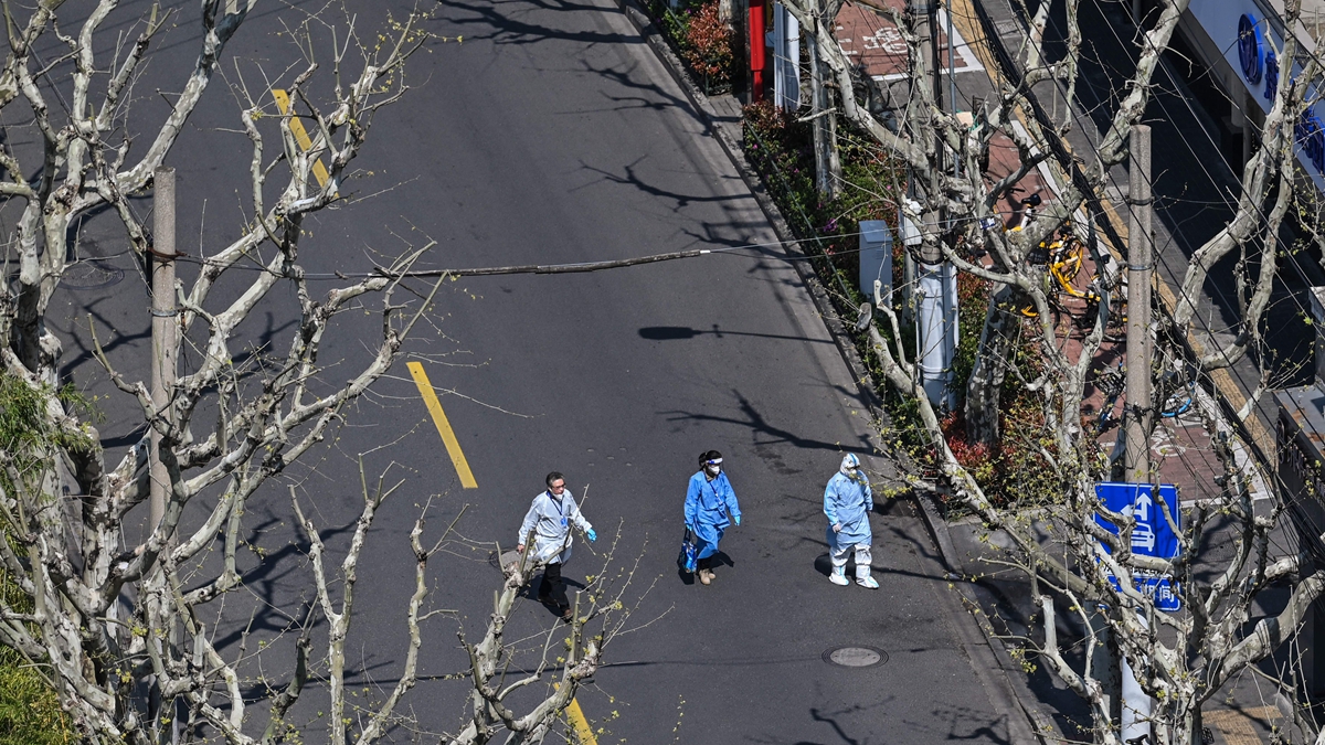 2022年4月3日,上海靜安區街道上,3名防疫人員在行走。(HECTOR RETAMAL/AFP via Getty Images)