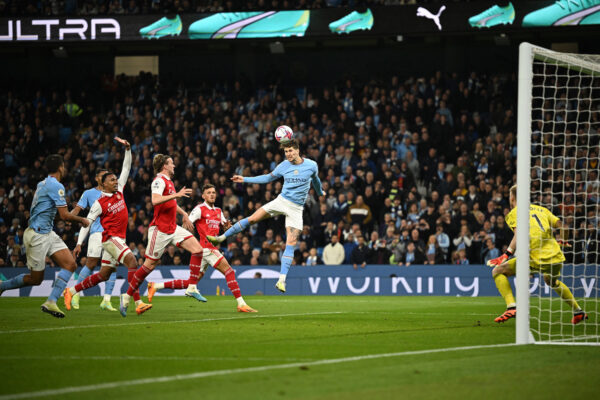 Manchester City's English defender John Stones (C) scores the team's second goal past Arsenal's English goalkeeper Aaron Ramsdale during the English Premier League football match between Manchester City and Arsenal at the Etihad Stadium in Manchester, north west England, on April 26, 2023. (Photo by Oli SCARFF / AFP) / RESTRICTED TO EDITORIAL USE. No use with unauthorized audio, video, data, fixture lists, club/league logos or 'live' services. Online in-match use limited to 120 images. An additional 40 images may be used in extra time. No video emulation. Social media in-match use limited to 120 images. An additional 40 images may be used in extra time. No use in betting publications, games or single club/league/player publications. / 