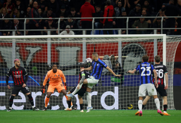 MILAN, ITALY - MAY 10: Edin Dzeko of FC Internazionale scores the team's first goal whilst under pressure as Mike Maignan of AC Milan looks on during the UEFA Champions League semi-final first leg match between AC Milan and FC Internazionale at San Siro on May 10, 2023 in Milan, Italy. 