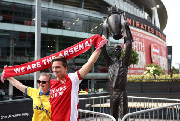 Fans pose for photographs with a statue of former Arsenal manager Arsene Wenger, outside of the Emirates Stadium in London on August 12, 2023, ahead of the English Premier League football match between Arsenal and Nottingham Forest. (Photo by HENRY NICHOLLS / AFP) / RESTRICTED TO EDITORIAL USE. No use with unauthorized audio, video, data, fixture lists, club/league logos or 'live' services. Online in-match use limited to 120 images. An additional 40 images may be used in extra time. No video emulation. Social media in-match use limited to 120 images. An additional 40 images may be used in extra time. No use in betting publications, games or single club/league/player publications. / 