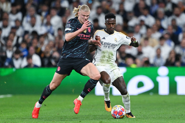 MADRID, SPAIN - APRIL 09: Vinicius Jr. of Real Madrid CF competes for the ball with Erling Haaland of Manchester City during the UEFA Champions League quarter-final first leg match between Real Madrid CF and Manchester City at Estadio Santiago Bernabeu on April 09, 2024 in Madrid, Spain. (Photo by David Ramos/Getty Images)