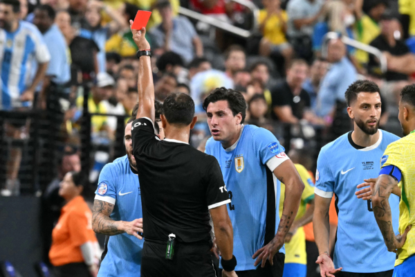 Argentine referee Dario Herrera (C) shows a red card to Uruguay's defender #08 Nahitan Nandez (L) during the Conmebol 2024 Copa America tournament quarterfinal football match between Uruguay and Brazil at Allegiant Stadium in Las Vegas, Nevada on July 6, 2024. (Photo by Frederic J. Brown / AFP) 