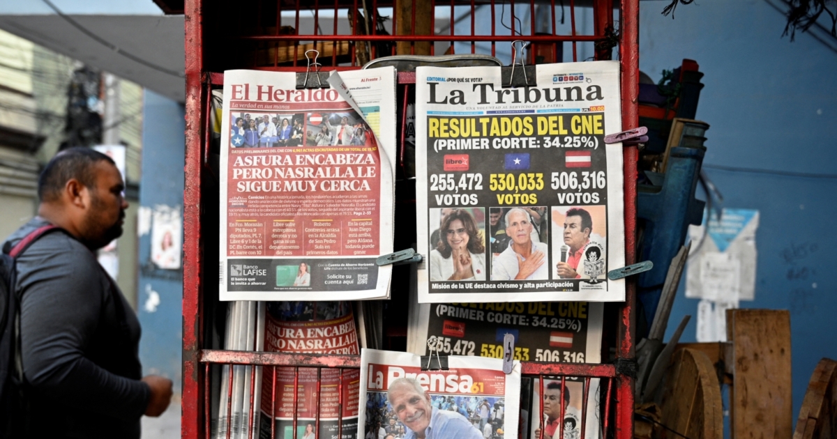 A man walks past a kiosk showing the front pages of newspapers in Tegucigalpa, on December 1, 2025, the day after the national election. Candidate Nasry Asfura, supported by US President Donald Trump, and his rival Salvador Nasralla, also from the right, are locked in a close race for victory in Honduras' presidential elections on Monday. (Photo by Orlando SIERRA / AFP)