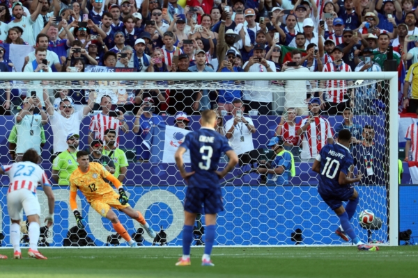 France's forward #10 Kylian Mbappe scores his team's first goal from the penalty spot past Paraguay's goalkeeper #12 Orlando Gill during the 2026 World Cup round of 16 football match between Paraguay and France at the Philadelphia Stadium in Philadelphia on July 4, 2026.