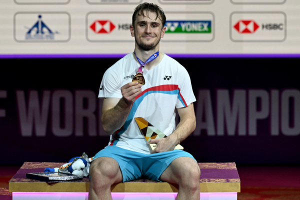 France's Alex Lanier celebrates on the podium during an awards ceremony after winning against Japan's Kodai Naraoka in their BWF World Championships men's singles final badminton match at the Indira Gandhi Indoor Stadium in New Delhi on August 23, 2026.